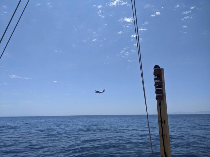 The Twin Otter research plane flies past RV Blissfully on sampling station. RV Blissfully’s surface light sensor is seen in the foreground. Photo by Bridget Seegers.